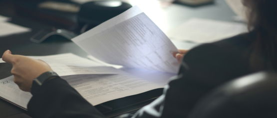 a woman sitting at a table reading a paper